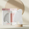 Face and neck massager roller with ergonomic design for skincare, displayed with packaging in a serene setting.