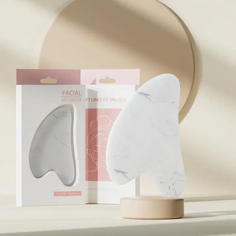 Face and neck massager roller with ergonomic design for skincare, displayed with packaging in a serene setting.