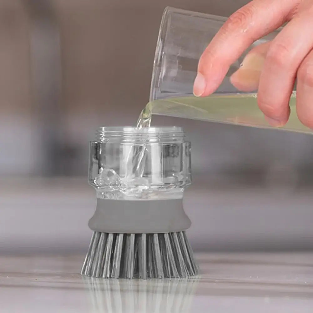 Hand pouring detergent into a multifunctional cleaning brush soap dispenser for easy kitchen cleaning.