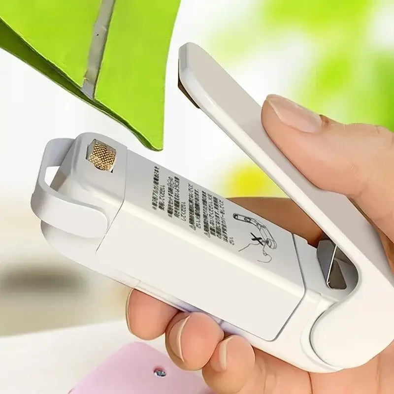 Hand using a Mini Heat Bag Sealing Machine to seal a bag, demonstrating its compact and portable design.