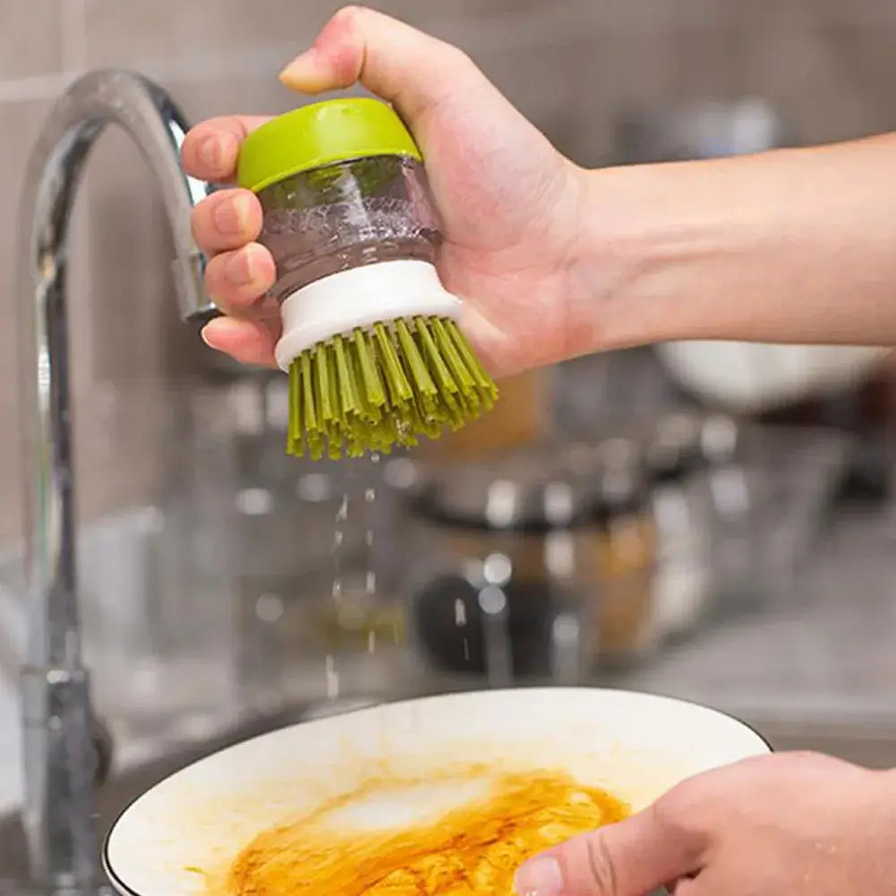 Hand using multifunctional cleaning brush soap dispenser on a frying pan for easy washing.