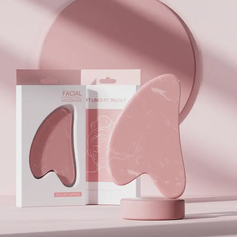 Pink facial massager on display with stylish packaging in a minimalist setting.